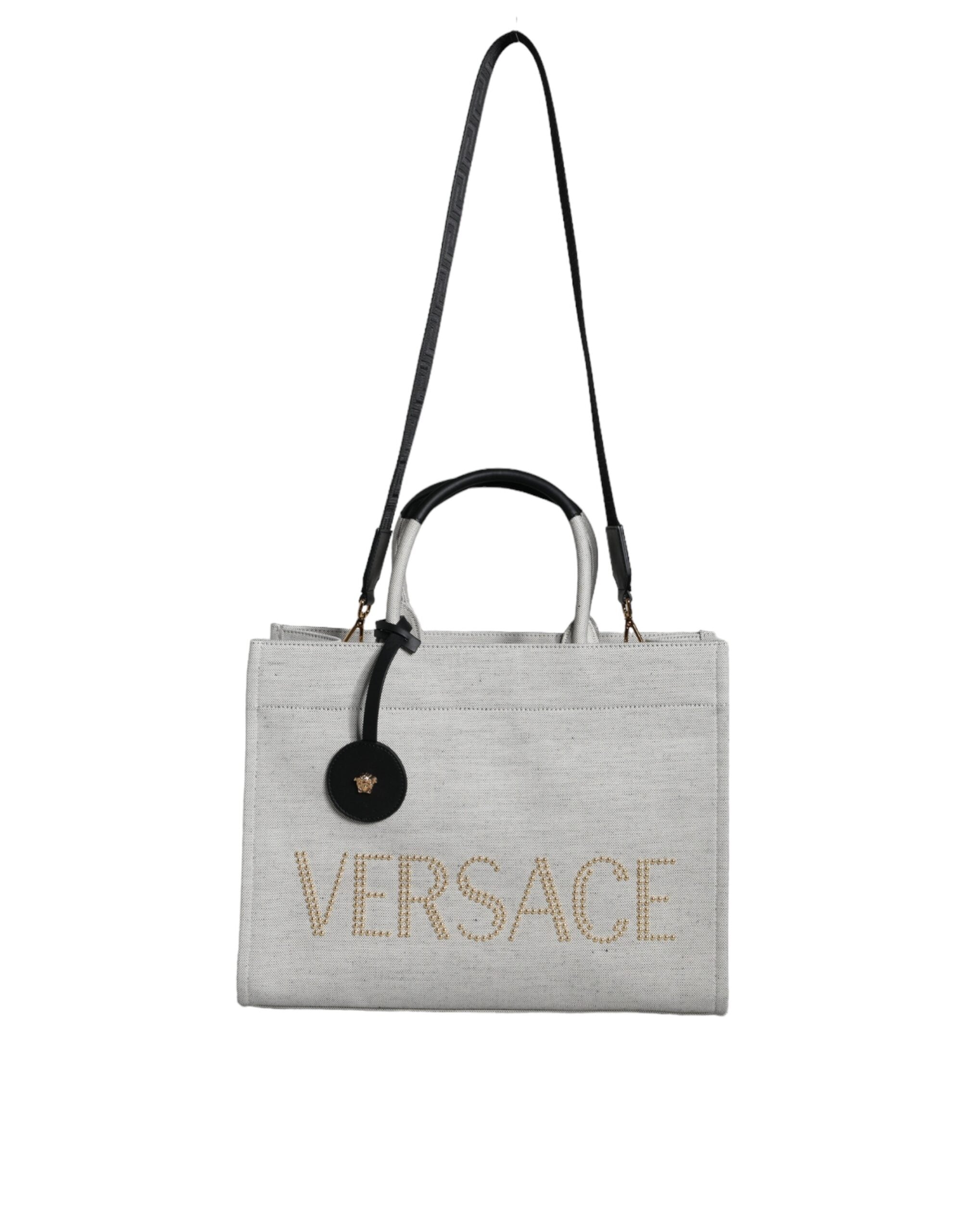Vit läderhandväska med läderdetaljer och logotyp, med övre handtag och som kan bäras som crossbody-väska.