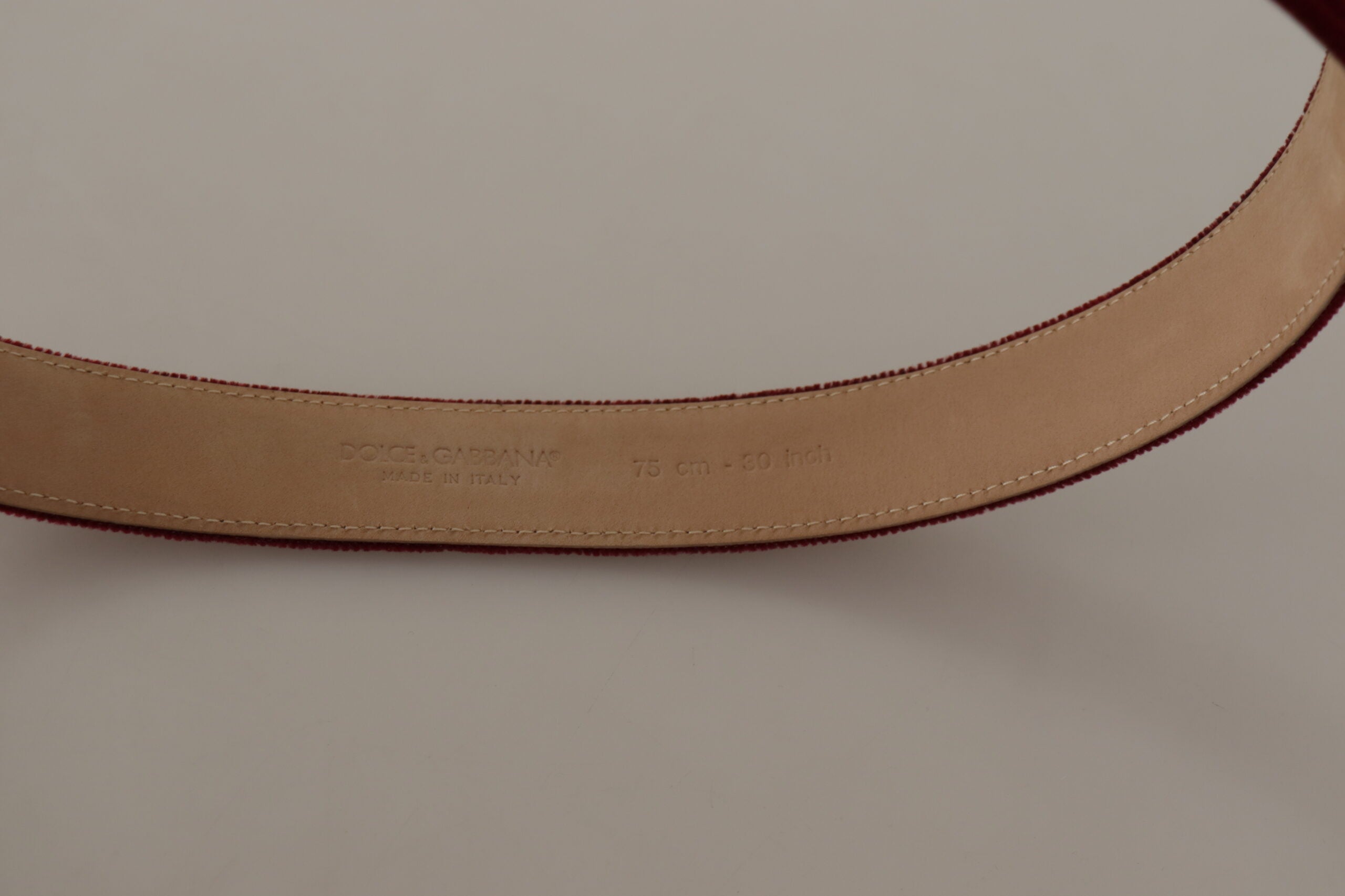 Röd sammet med silverfärgad logogravyr och metallspänne på bältet.