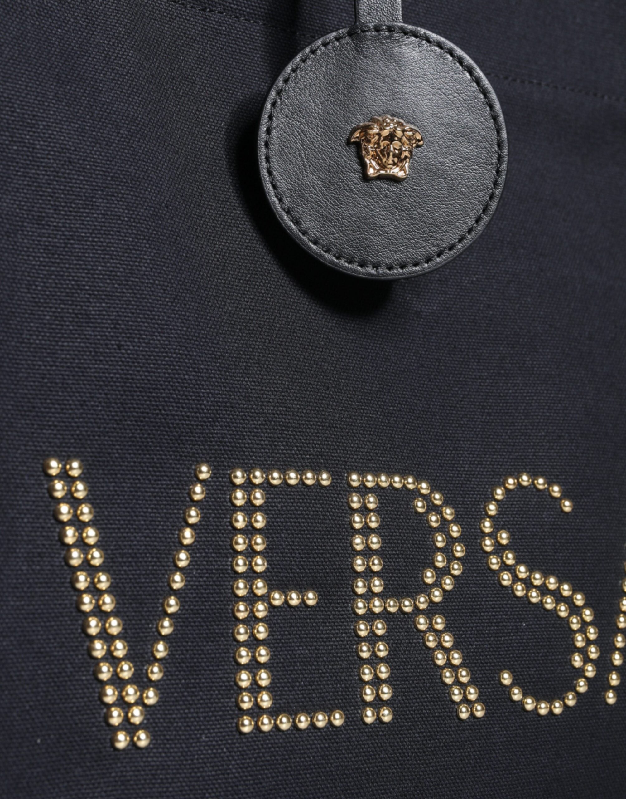 Svart handväska i läder och canvas med logotyp, bärs i handen eller över axeln.