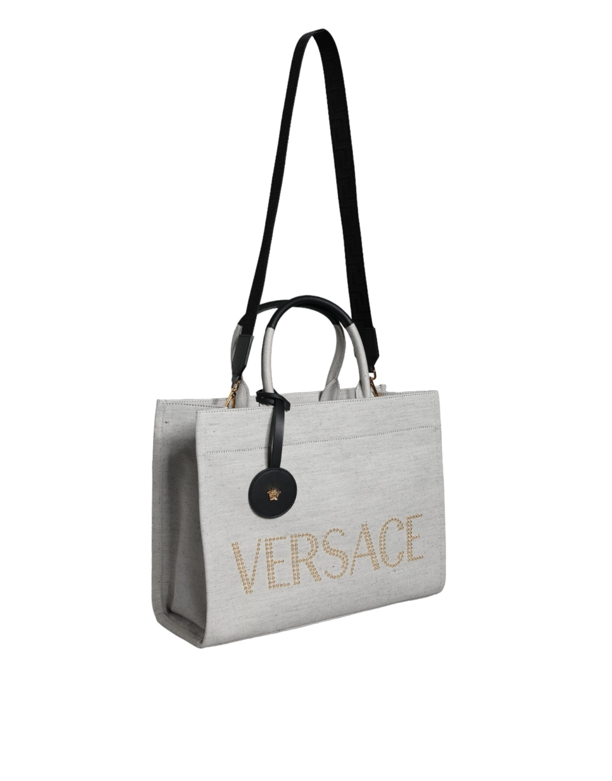 Vit läderhandväska med läderdetaljer och logotyp, med övre handtag och som kan bäras som crossbody-väska.