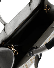 Vit läderhandväska med läderdetaljer och logotyp, med övre handtag och som kan bäras som crossbody-väska.
