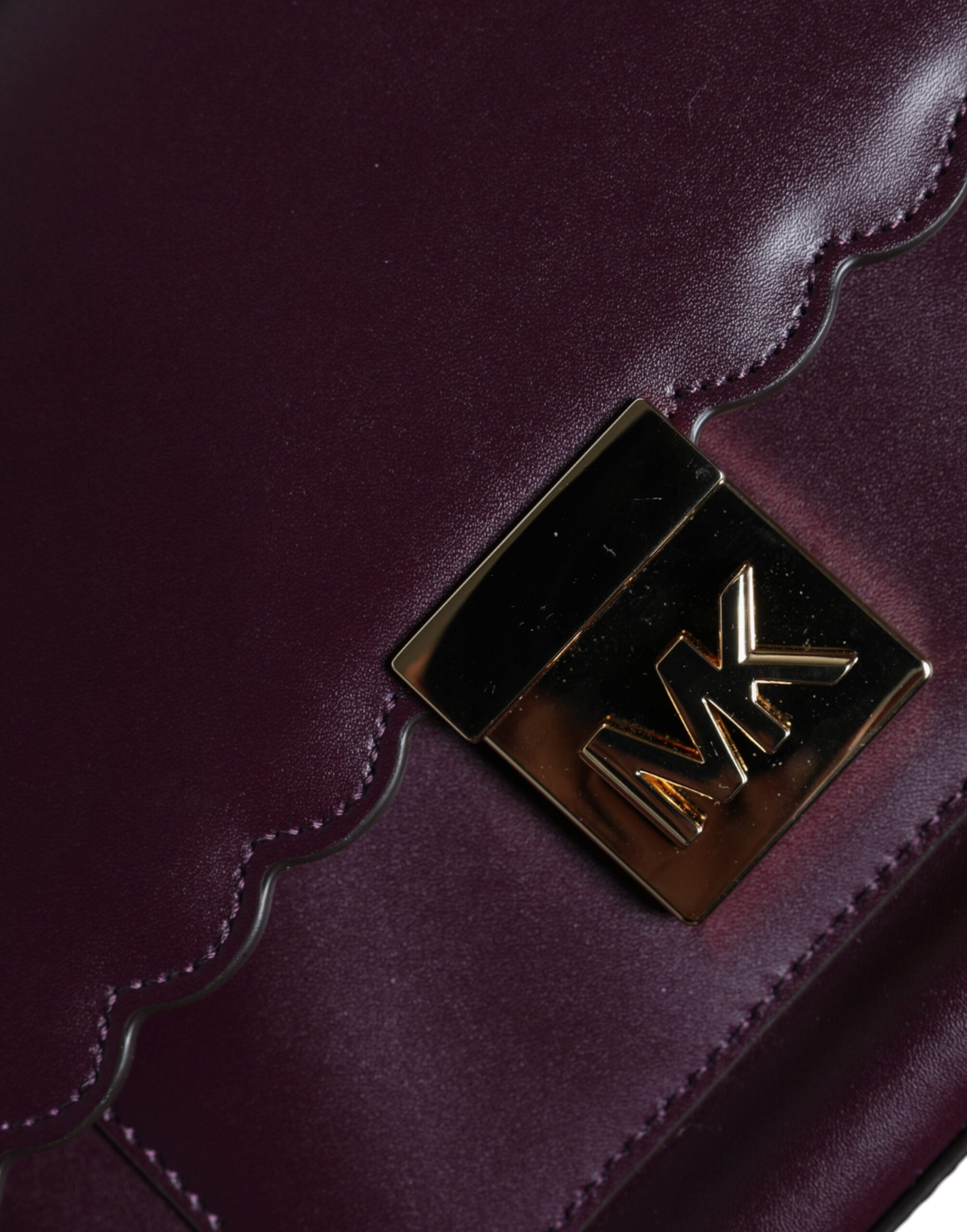 Purpurfärgad läderhandväska med logoplack, MINDY-modell, som bärs över axeln.