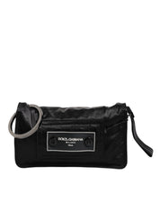 Svart väska i tyg med logotyp, kan bäras som clutch eller crossbody.
