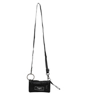 Svart väska i tyg med logotyp, kan bäras som clutch eller crossbody.