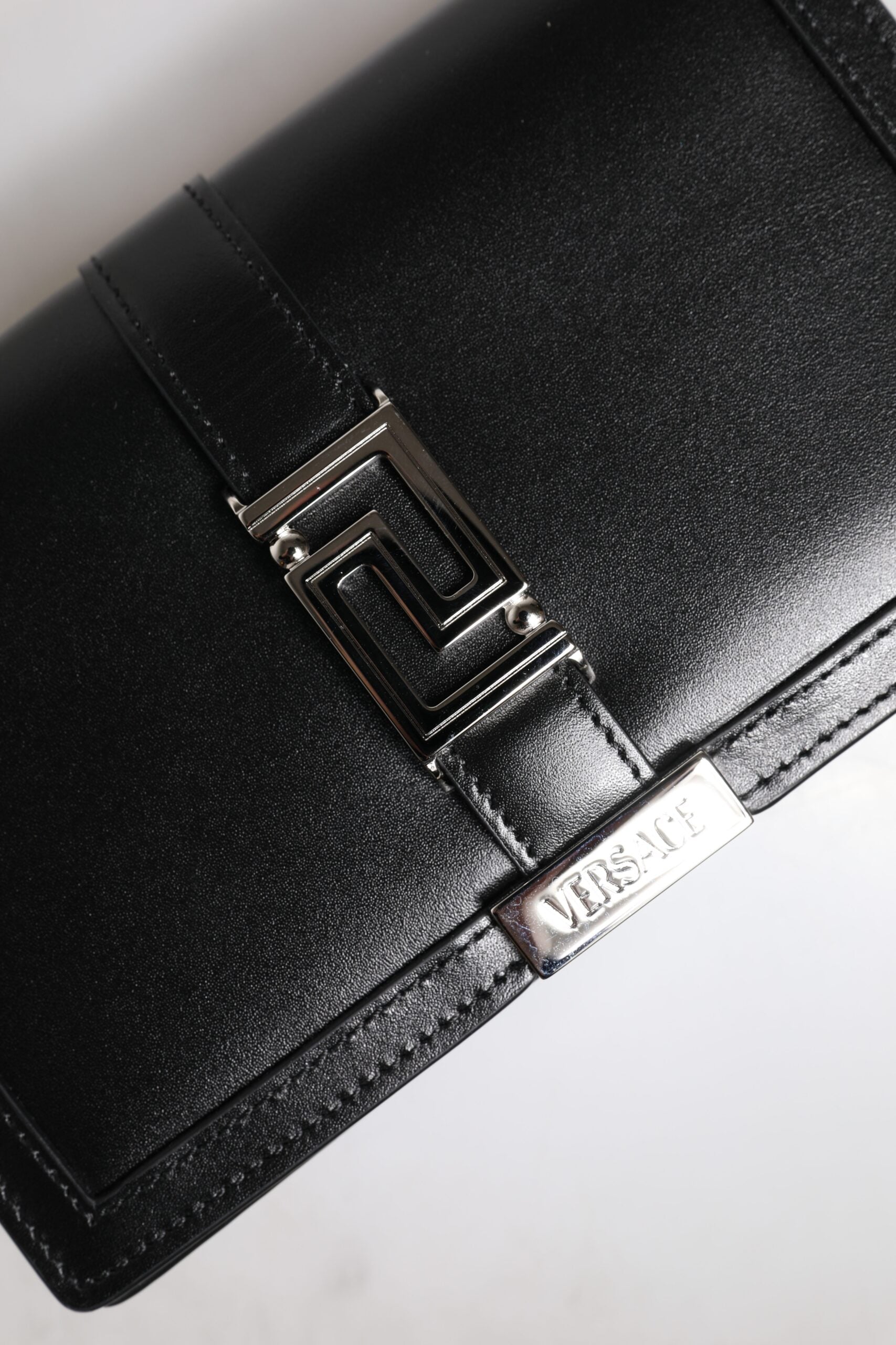 Svart läderhandväska i kalvskinn med kedjeband, för att bära över axeln eller som crossbody-väska.