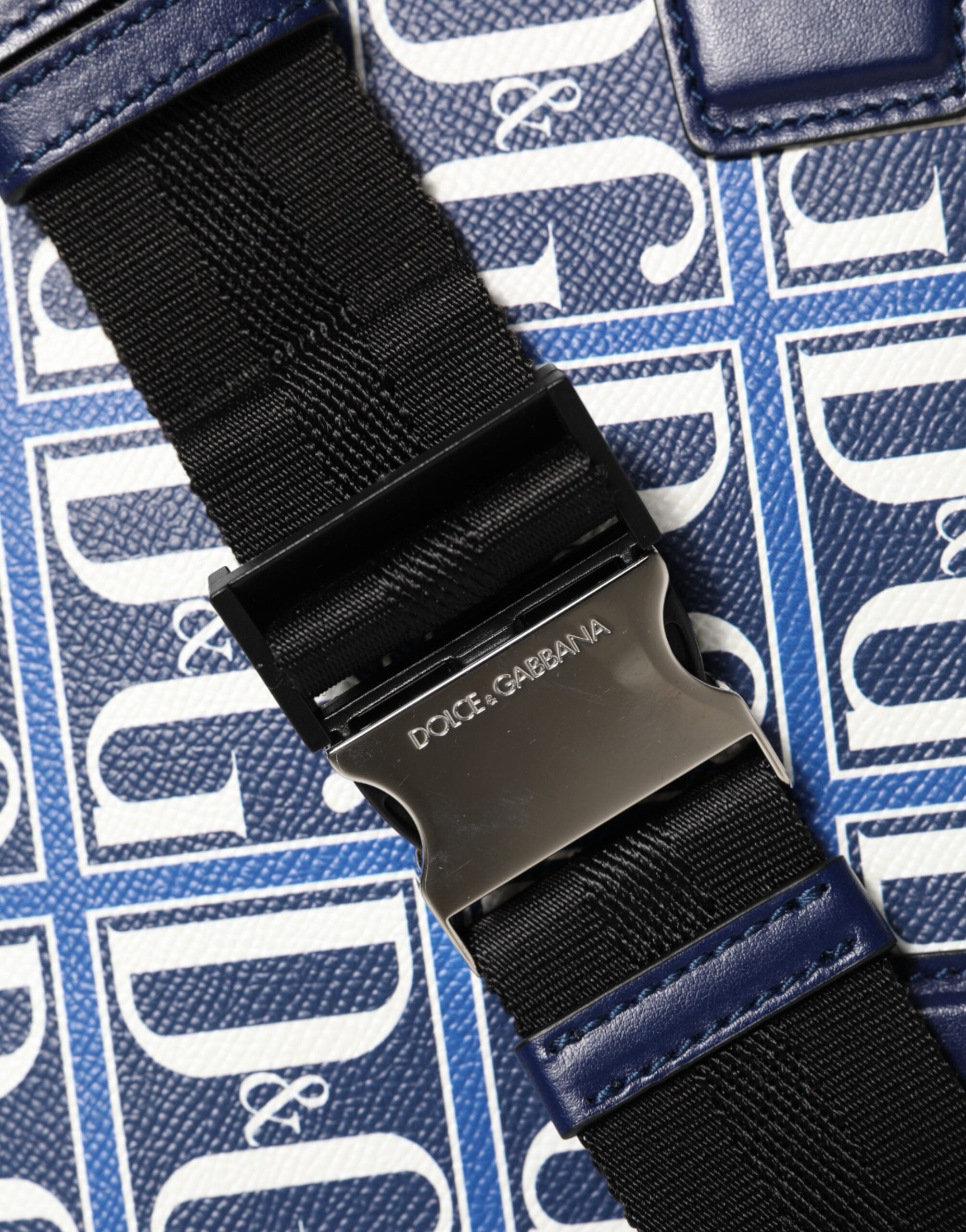 Blå vit läderhandväska med D&amp;G-logoplack, bärs över axeln.