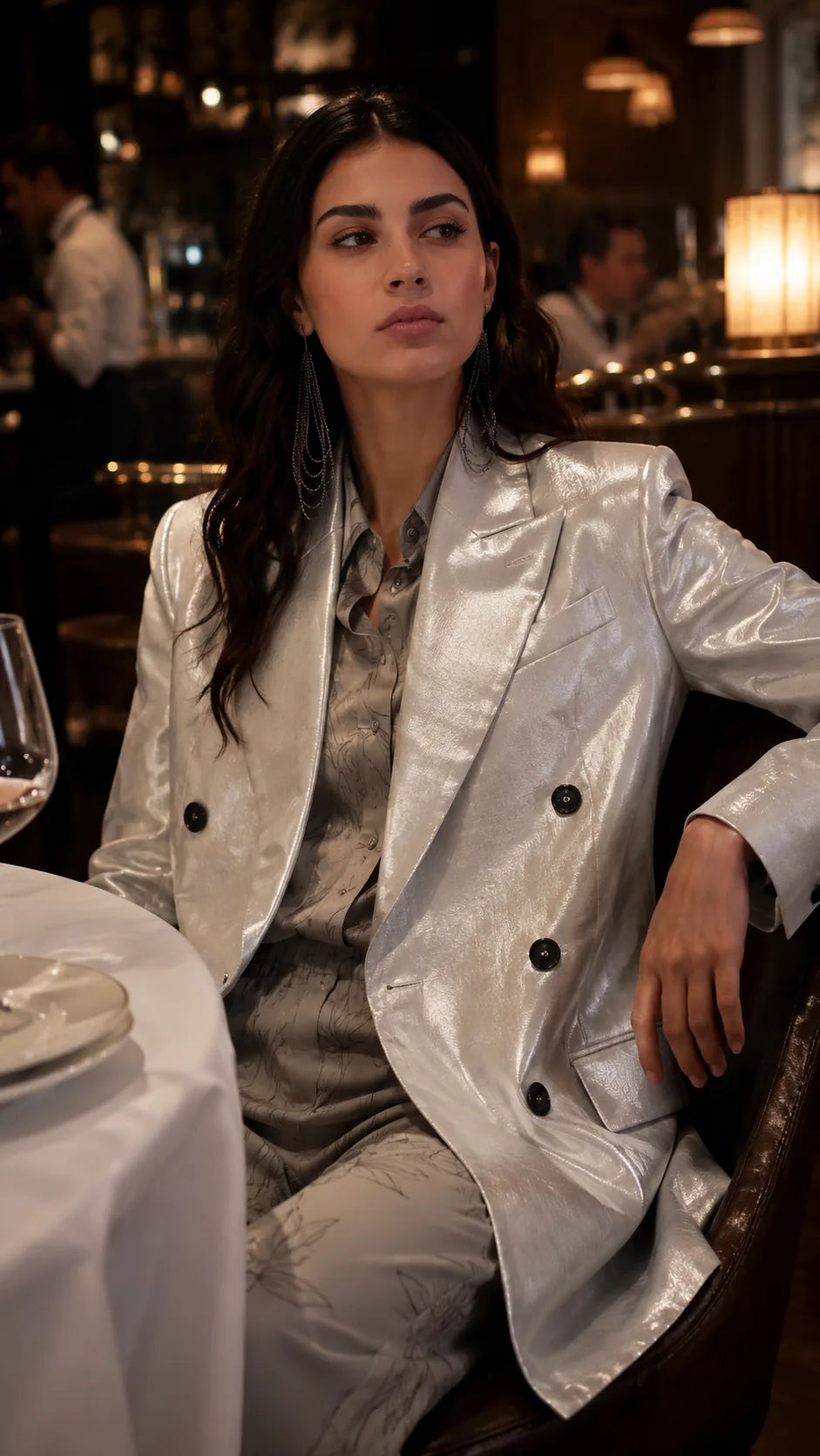 Woman in a silver jacket sitting at a table in a restaurant.